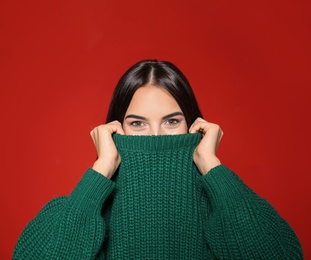 Image of Pretty woman wearing warm sweater on red background 