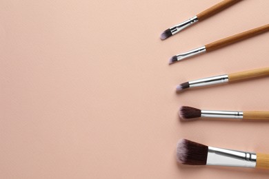 Photo of Set of makeup brushes on beige background, flat lay. Space for text