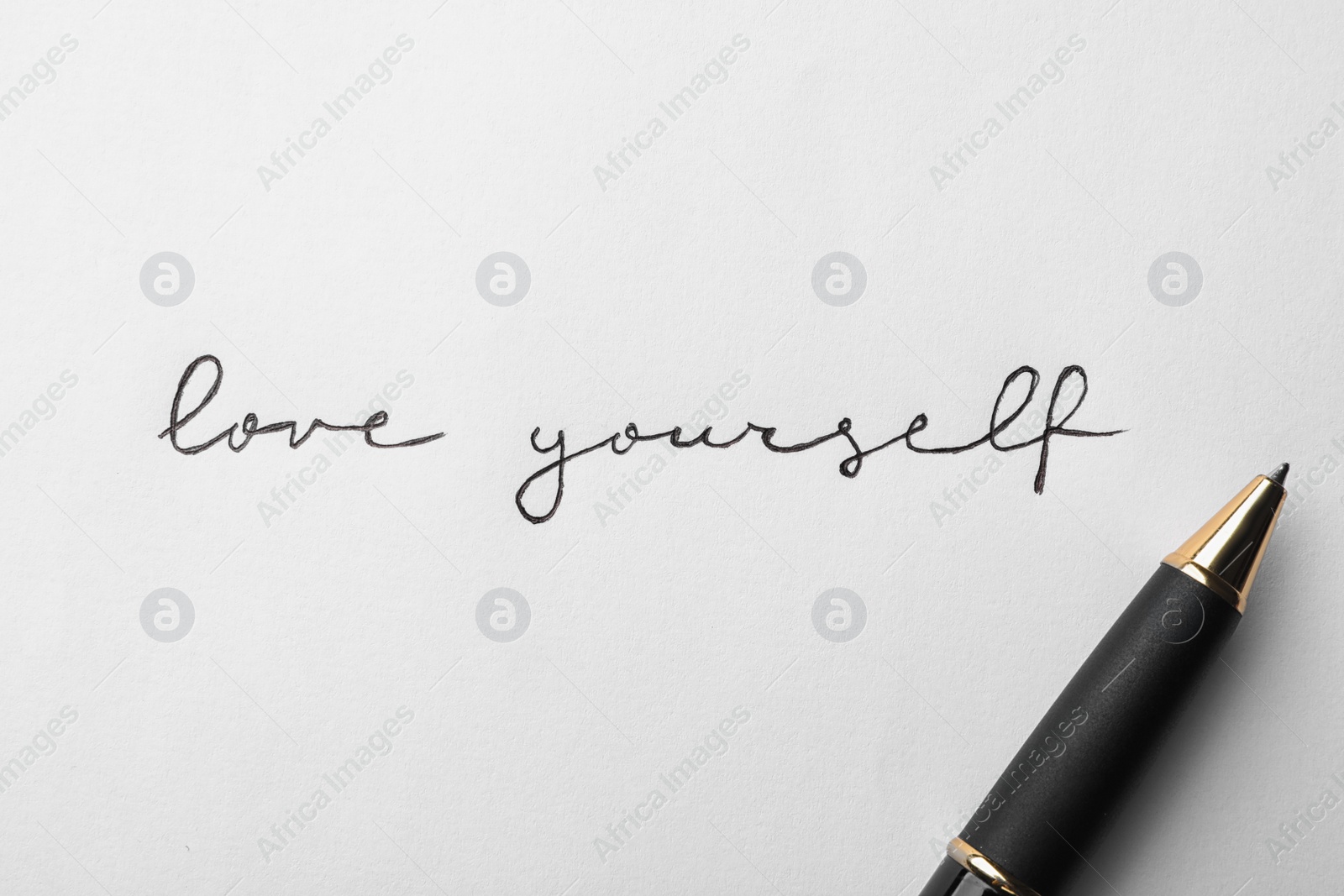 Photo of Written words LOVE YOURSELF and pen on white background, top view