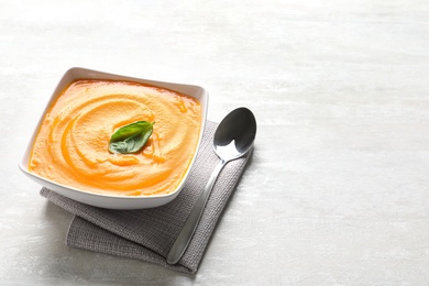 Photo of Bowl of tasty pumpkin soup on light background. Space for text