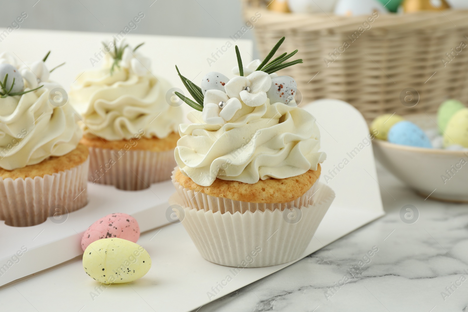 Photo of Tasty Easter cupcakes with vanilla cream on white marble table