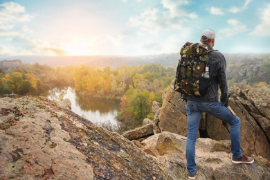 Photo of Traveler with backpack enjoying beautiful view near mountain river. Autumn vacation