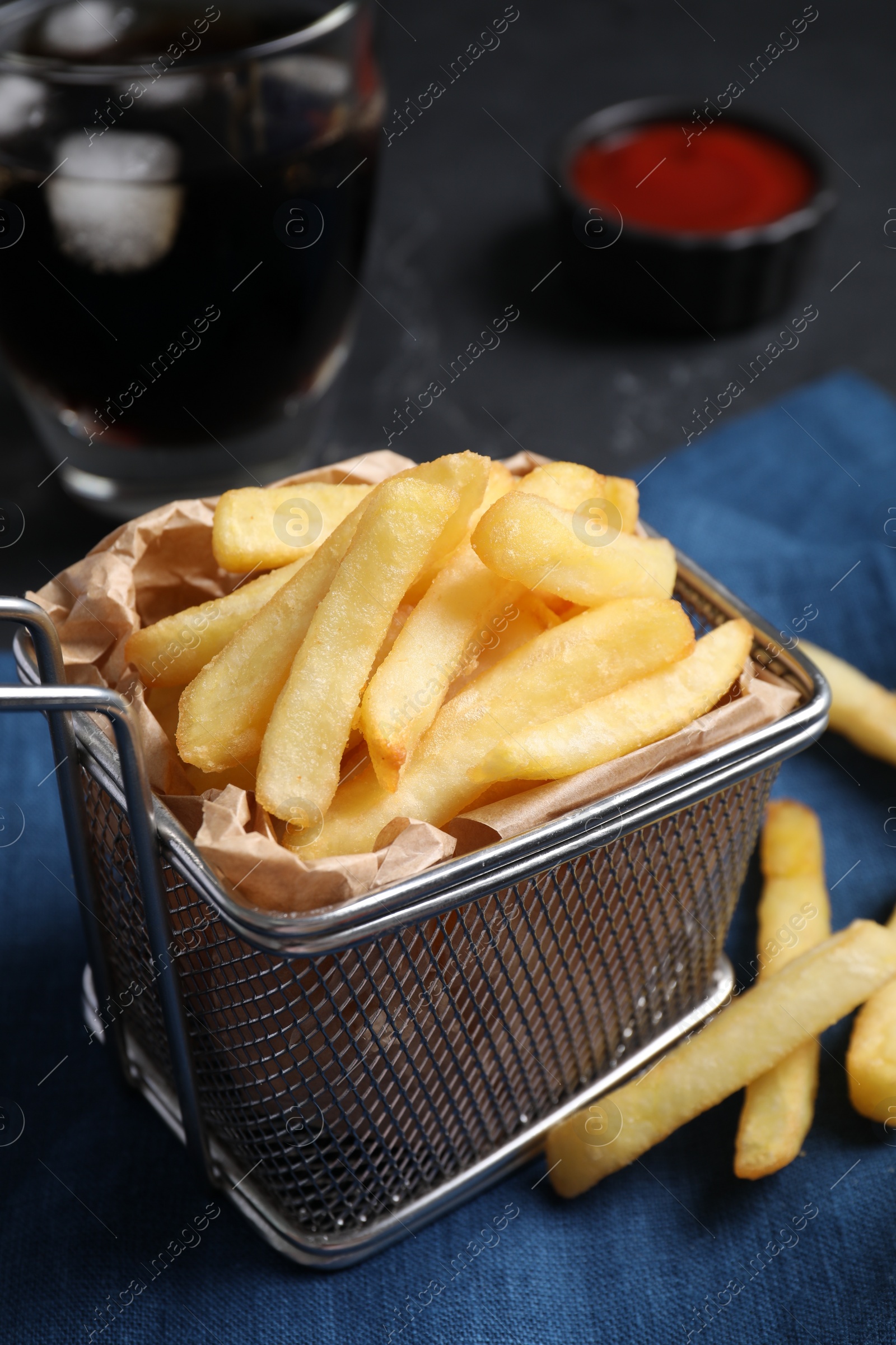 Photo of Frying basket with tasty french fries on table, closeup