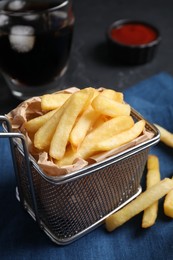 Photo of Frying basket with tasty french fries on table, closeup