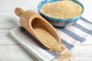 Photo of Bowl and scoop with white quinoa on wooden table