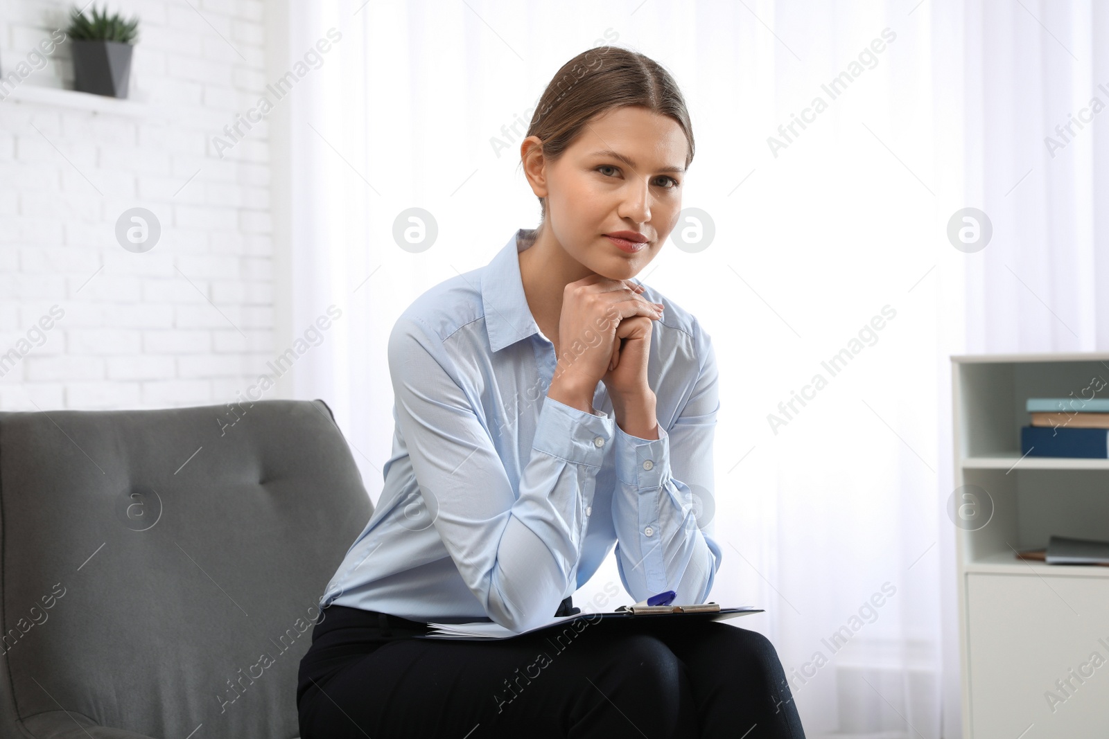 Photo of Professional psychotherapist with clipboard in modern office