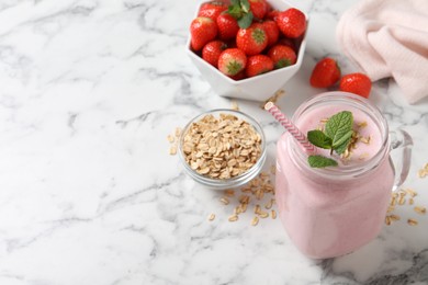 Mason jar of tasty strawberry smoothie with oatmeal and mint on white marble table, space for text