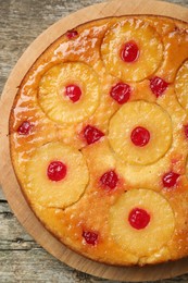 Tasty pineapple cake with cherries on wooden table, top view