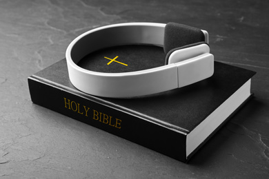 Photo of Bible and headphones on black background. Religious audiobook