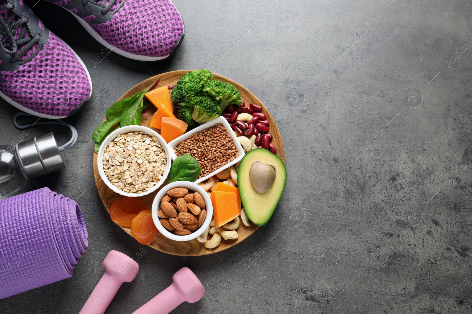 Photo of Plate with heart-healthy products and sports equipment on grey background, flat lay. Space for text