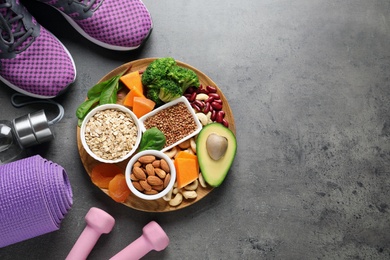 Photo of Plate with heart-healthy products and sports equipment on grey background, flat lay. Space for text