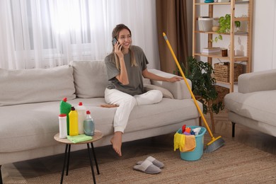 Photo of Young mother talking on phone in messy living room