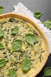 Delicious homemade spinach pie on black table, flat lay