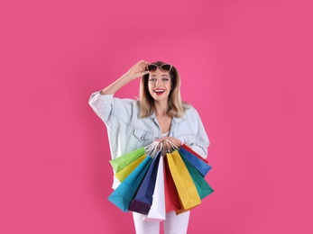 Photo of Beautiful young woman with shopping bags on color background