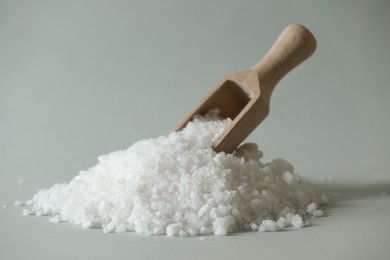 Photo of Organic salt and wooden scoop on light grey background, closeup