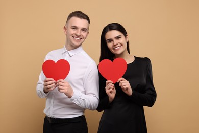Photo of Lovely couple with decorative hearts on beige background. Valentine's day celebration