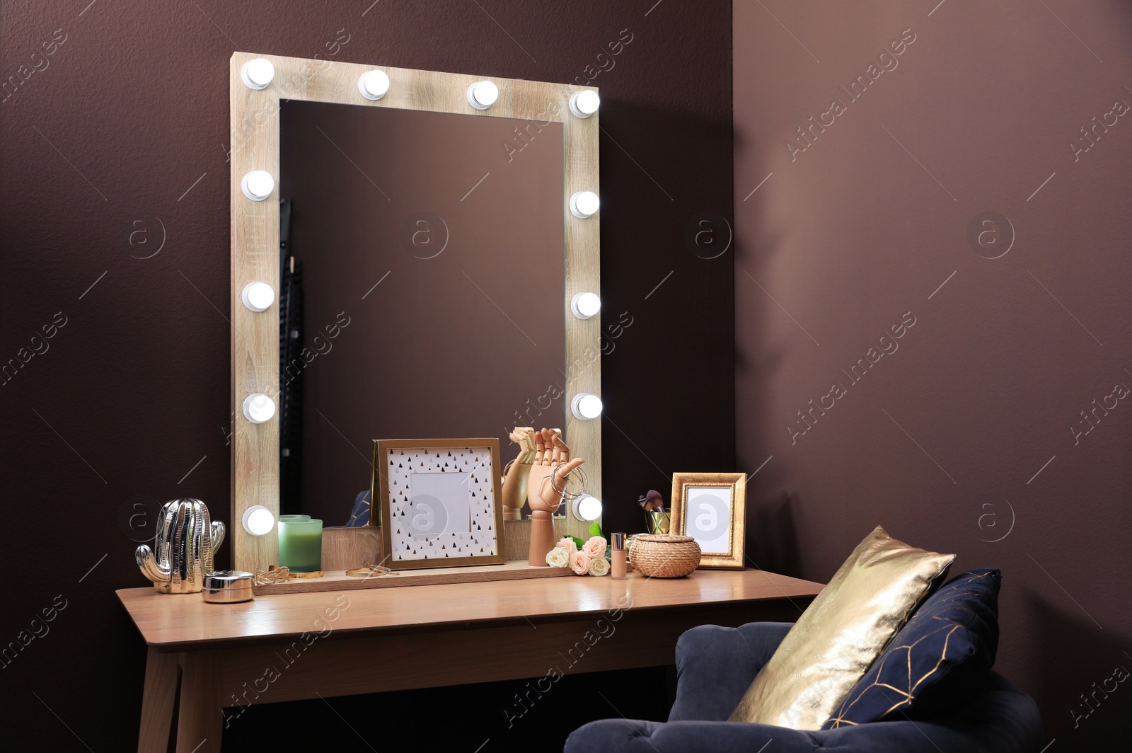Photo of Stylish dressing table with mirror near brown wall in room