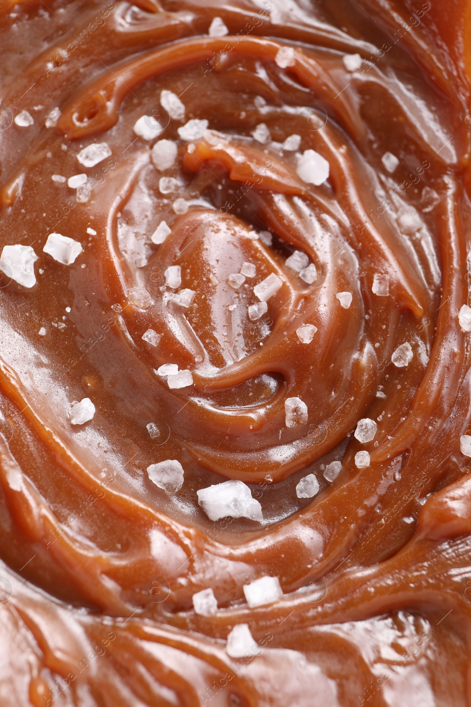 Photo of Tasty caramel sauce and salt as background, above view
