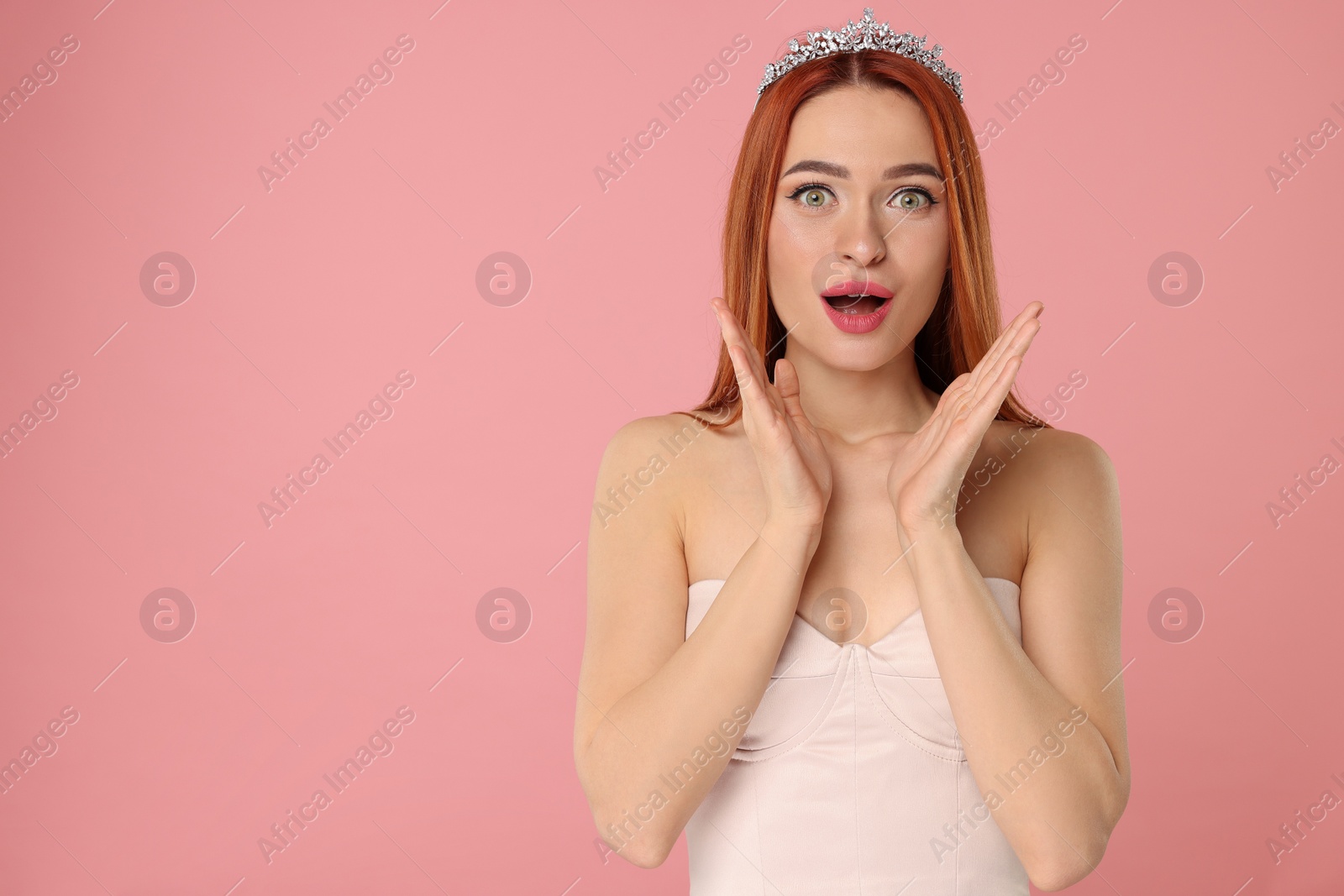 Photo of Emotional young woman with tiara on pink background, space for text