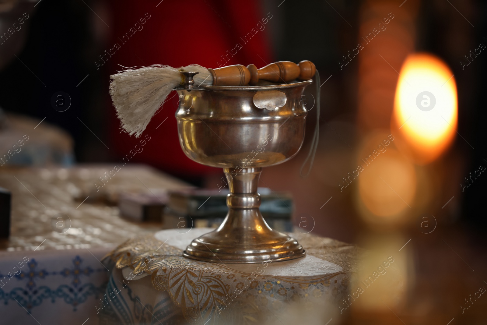 Photo of Silver vessel with holy water and brush on stand in church. Baptism ceremony