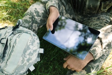 Soldier with backpack using tablet in forest, closeup