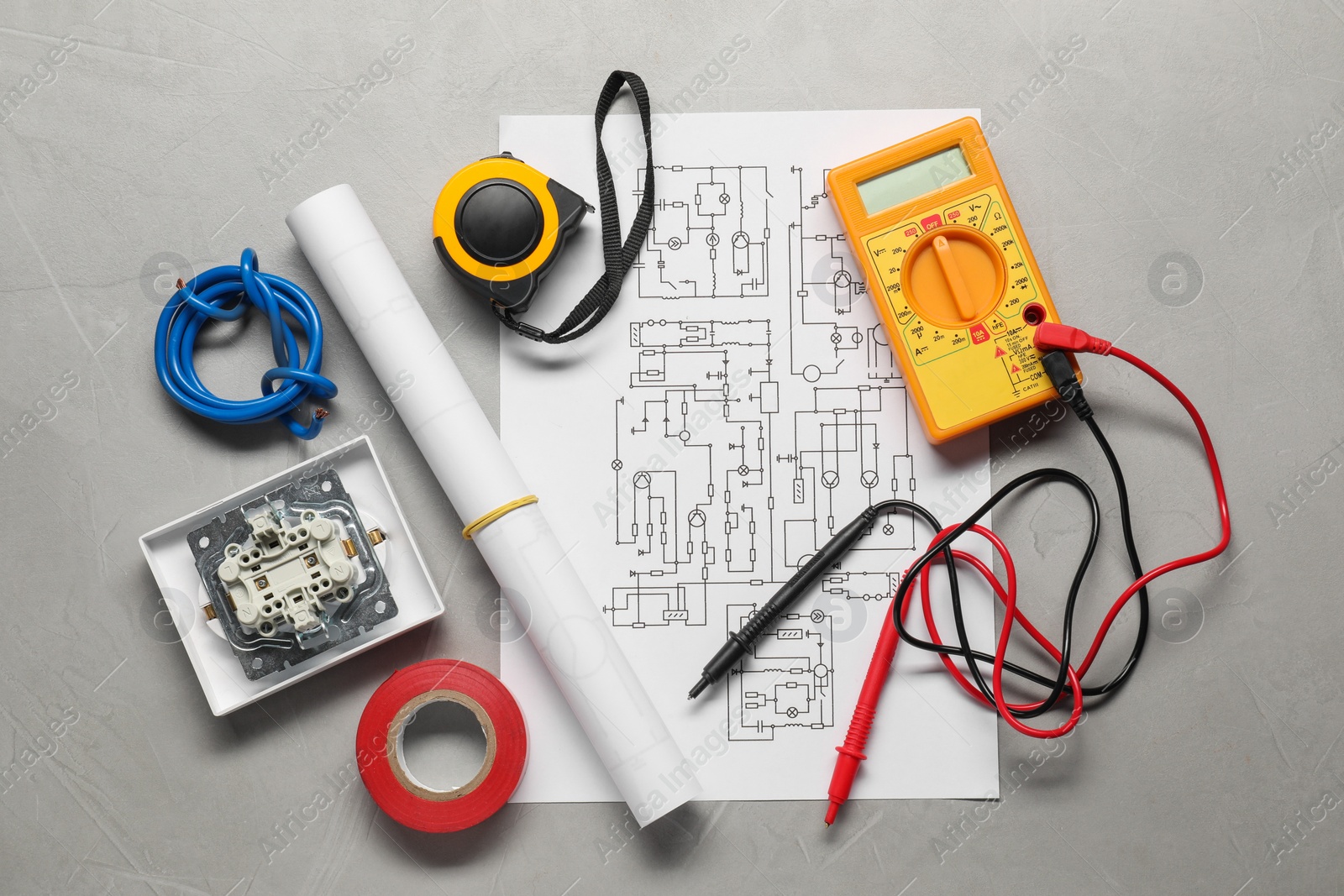 Photo of Wiring diagram, wires and digital multimeter on light grey table, flat lay