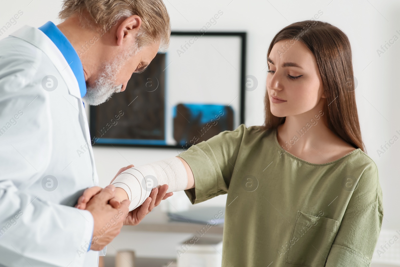 Photo of Orthopedist applying bandage onto patient's elbow in clinic
