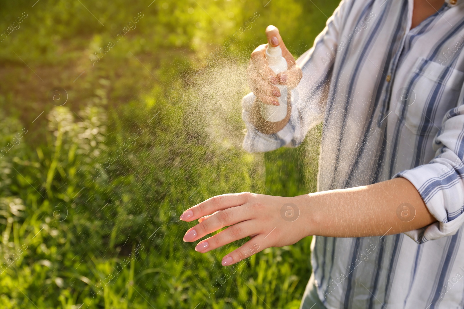 Photo of Woman applying insect repellent on hand in park, closeup. Tick bites prevention