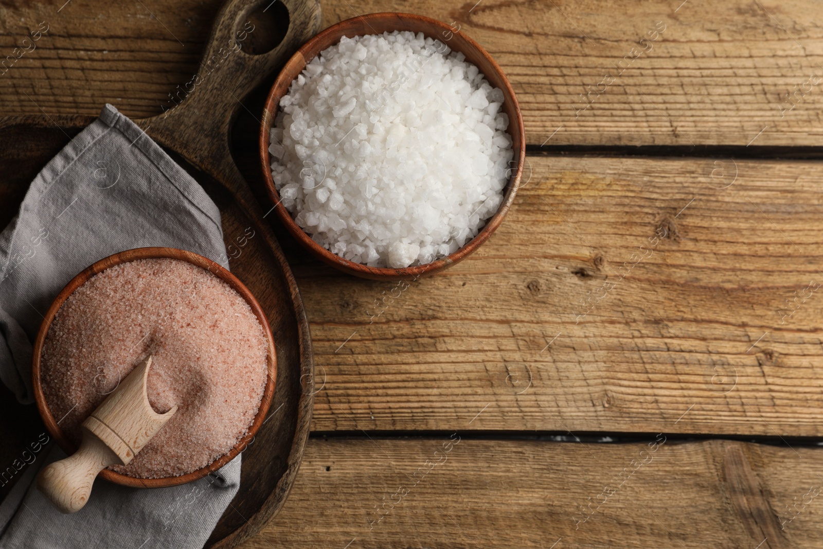 Photo of Different natural salt on wooden table, flat lay. Space for text