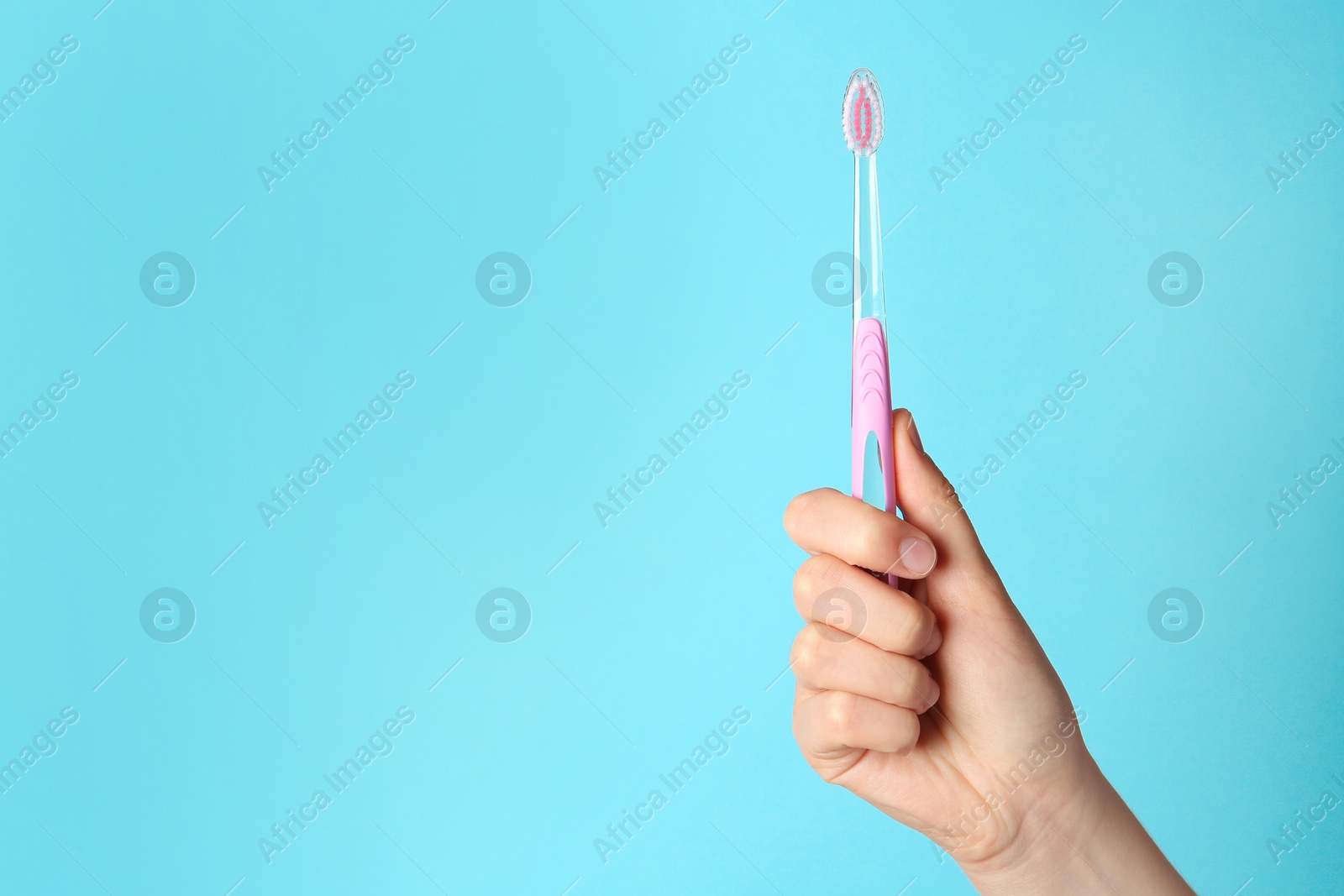 Photo of Woman holding manual toothbrush against color background