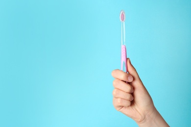 Woman holding manual toothbrush against color background