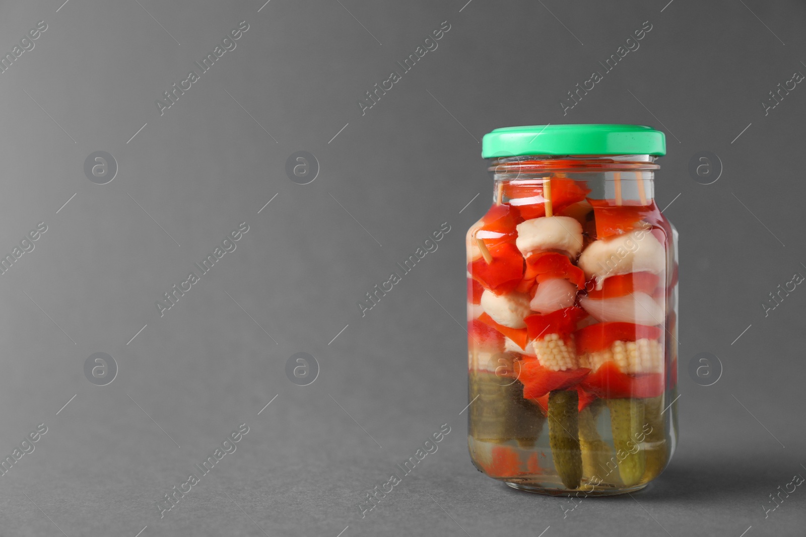Photo of Jar with pickled vegetables on grey background. Space for text