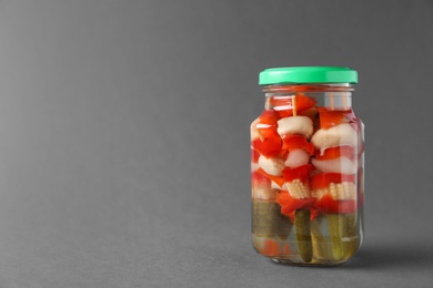 Jar with pickled vegetables on grey background. Space for text