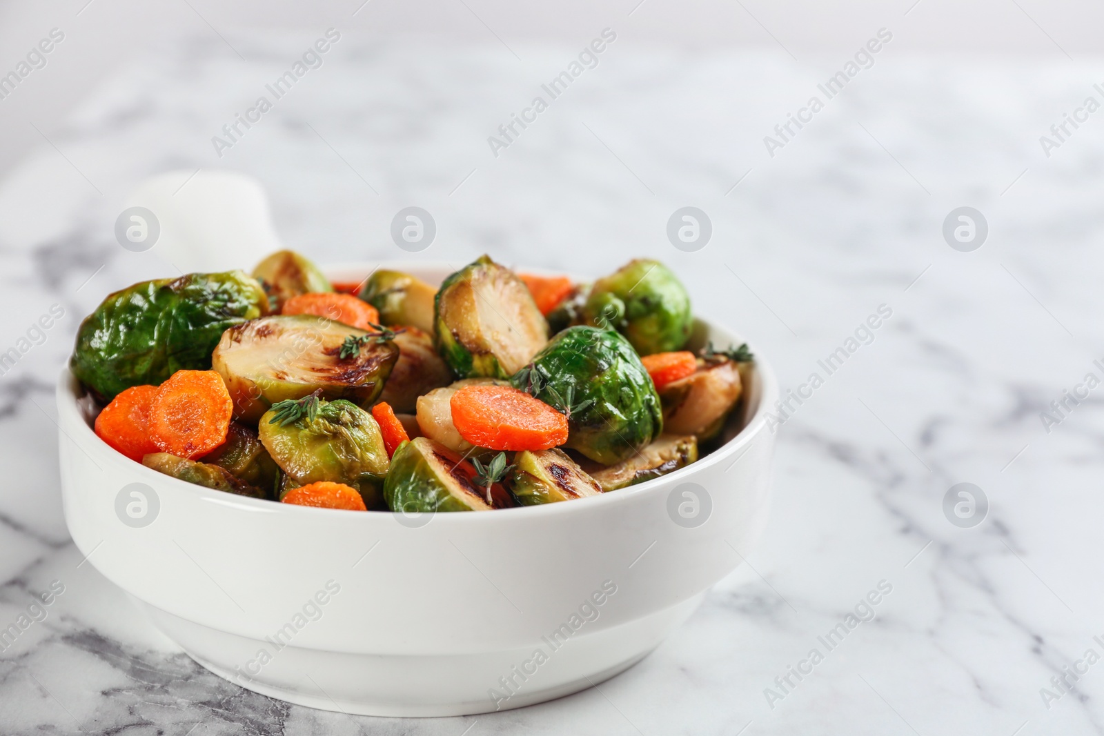 Photo of Delicious roasted Brussels sprouts with carrot on white marble table, closeup