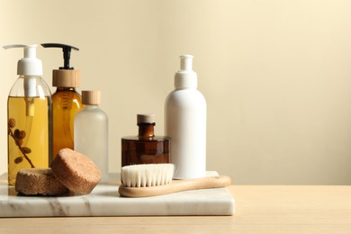 Different bath accessories on wooden table against beige background. Space for text