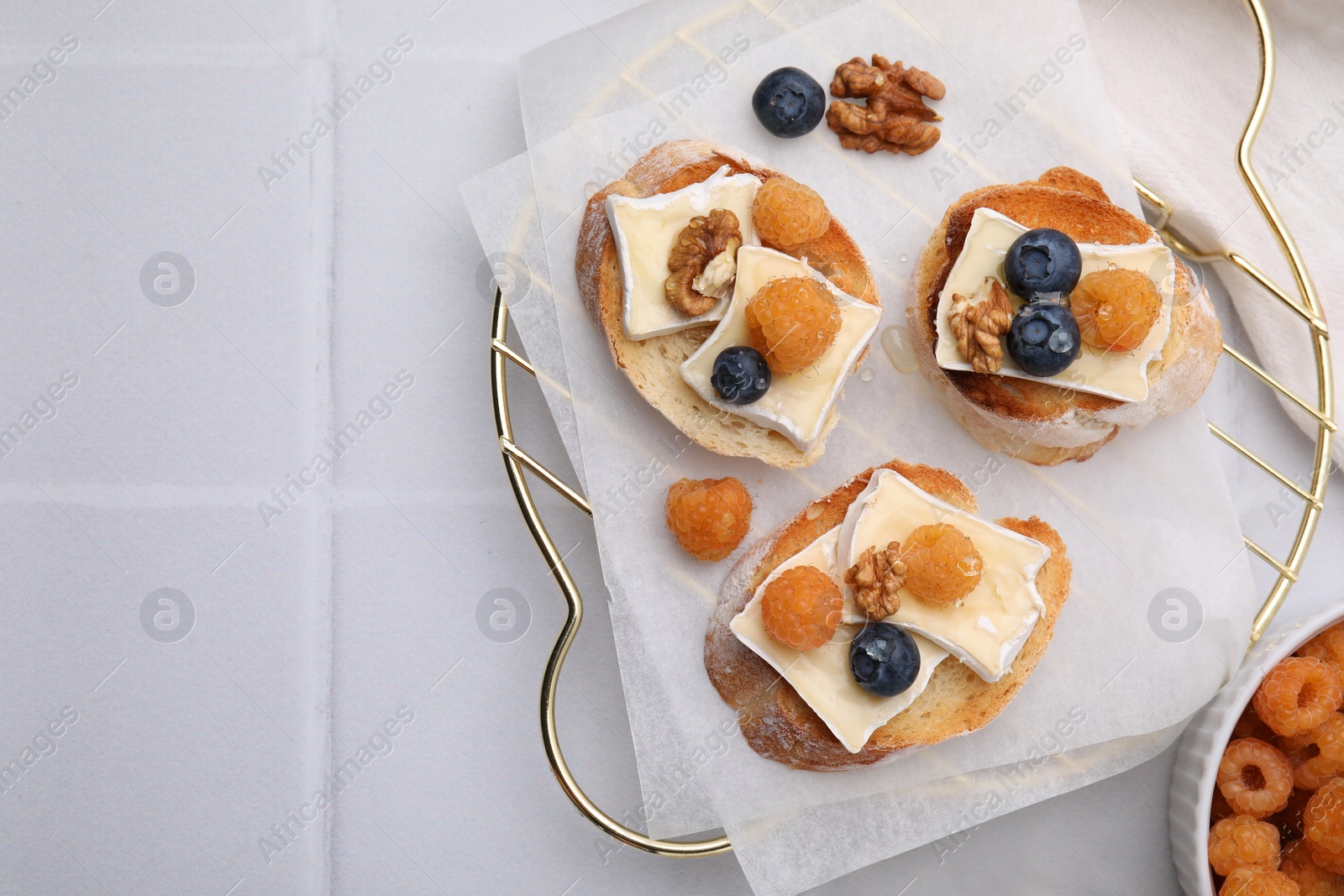 Photo of Tasty brie cheese sandwiches on white tiled table, flat lay. Space for text