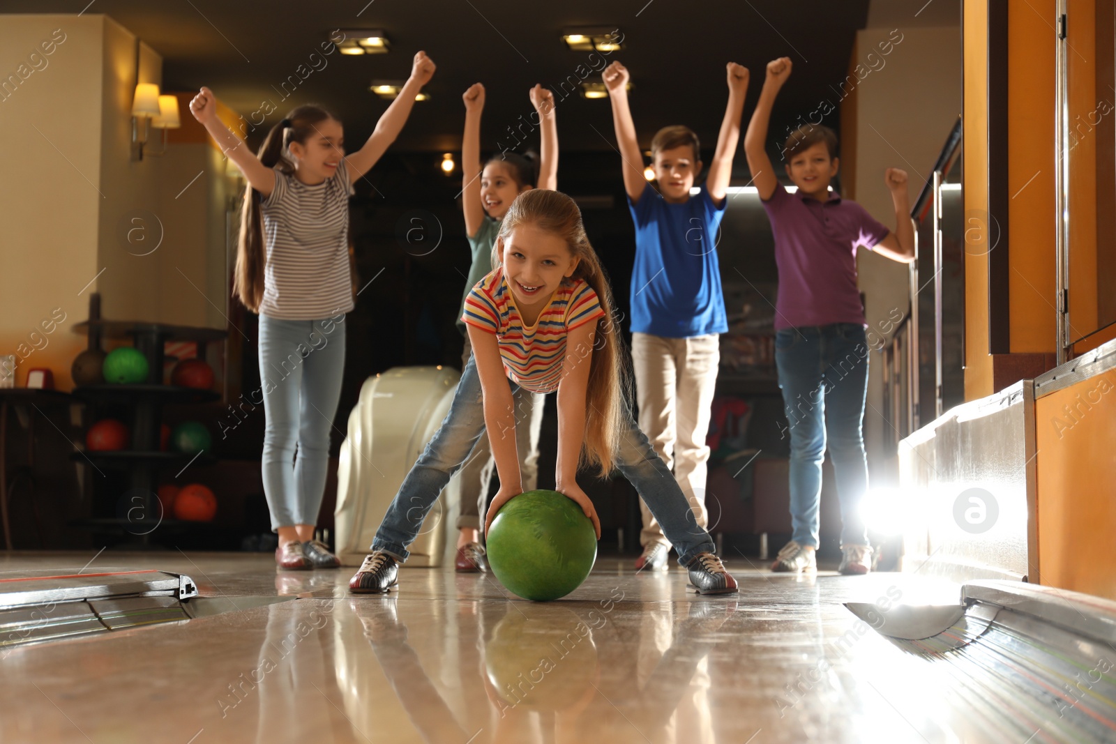 Photo of Girl throwing ball and spending time with friends in bowling club