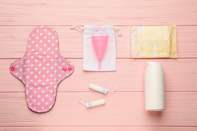 Cloth menstrual pad and other female hygiene products on pink wooden table, flat lay