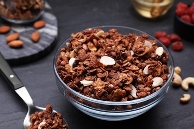 Photo of Tasty granola served with nuts and dry fruits on black table