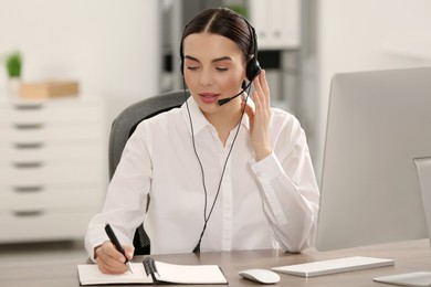 Photo of Hotline operator with headset and notebook working in office