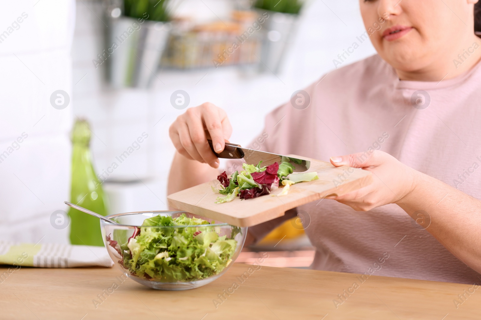 Photo of Overweight woman preparing salad in kitchen. Healthy diet