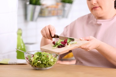 Overweight woman preparing salad in kitchen. Healthy diet