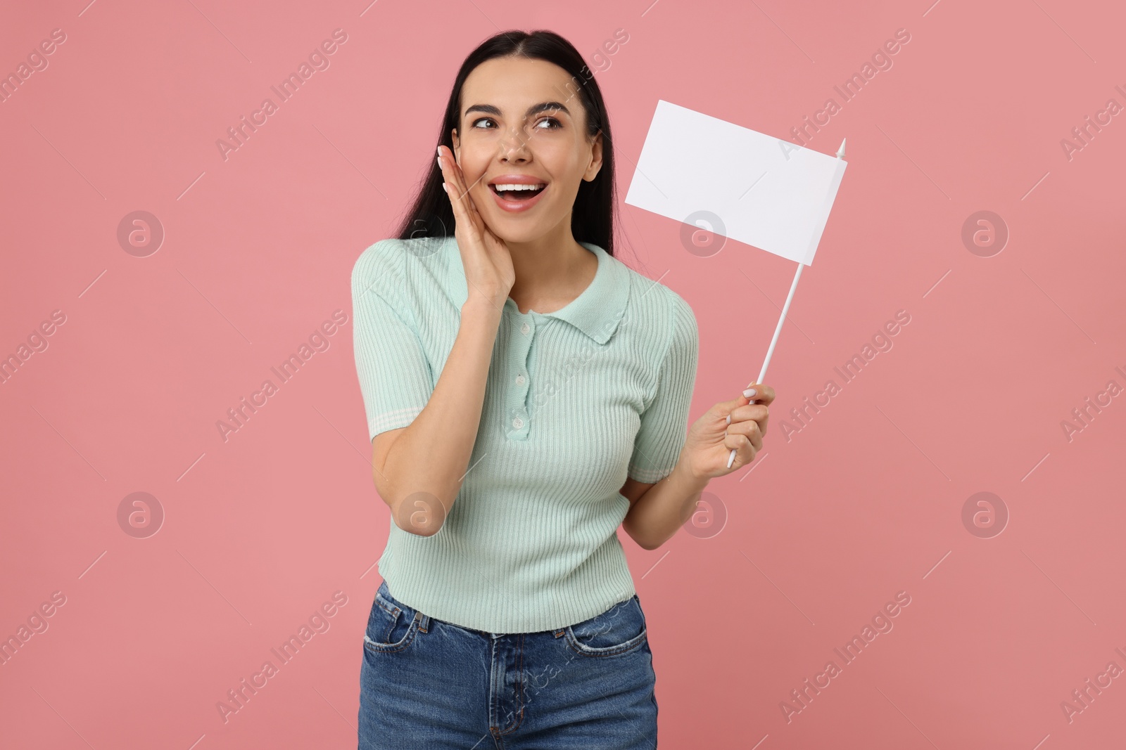 Photo of Emotional young woman with blank white flag on pink background. Mockup for design