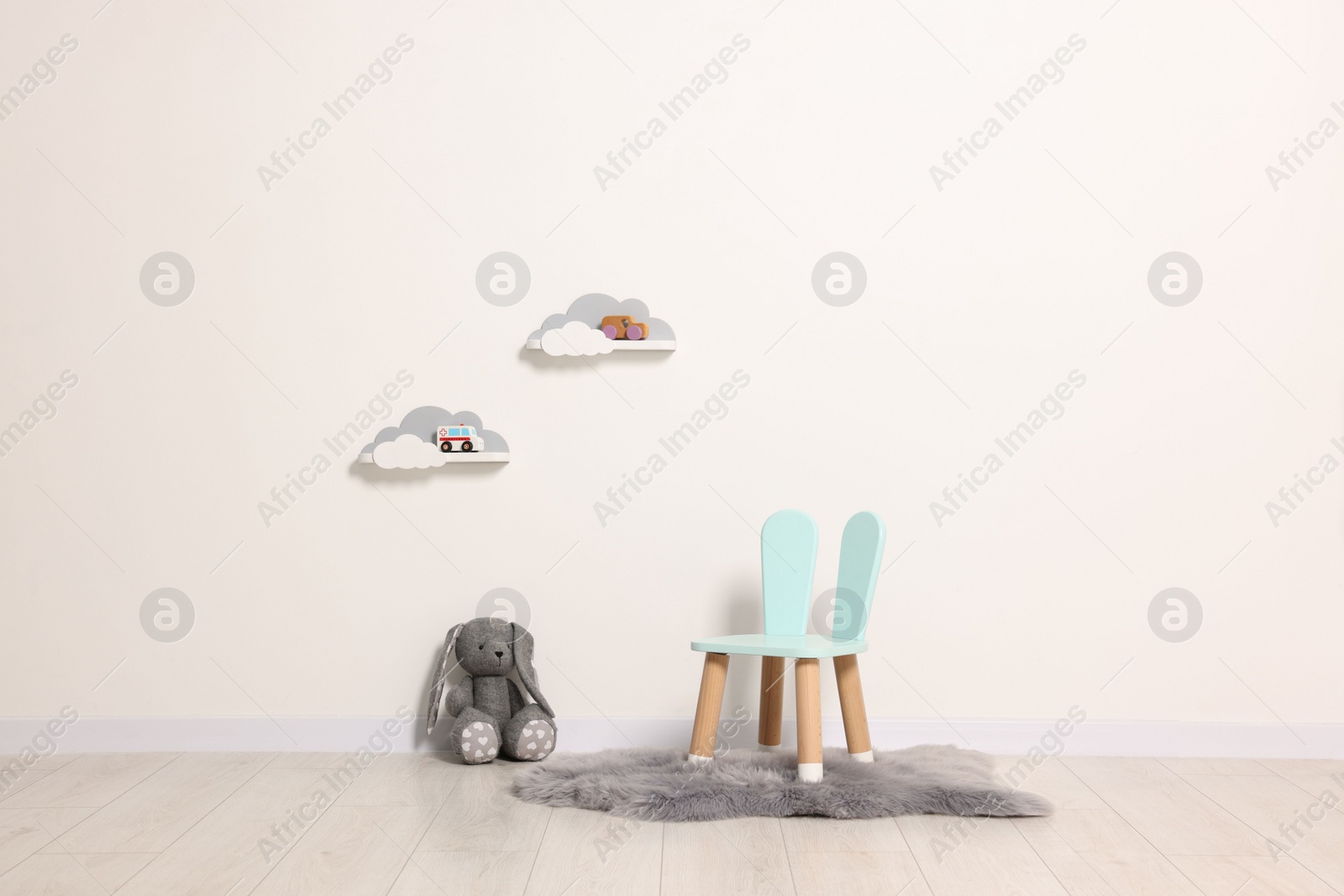 Photo of Beautiful children's room with light wall, chair and toys. Interior design