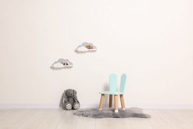 Beautiful children's room with light wall, chair and toys. Interior design