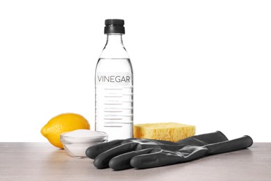 Photo of Natural cleaning products. Vinegar in bottle, baking soda, glove, sponge and lemon on light wooden table against white background