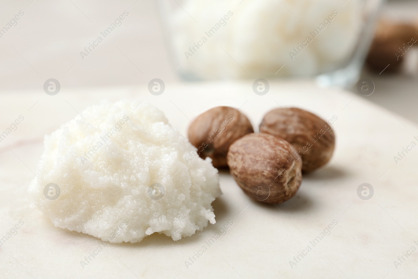 Photo of Shea butter and nuts on marble board, closeup