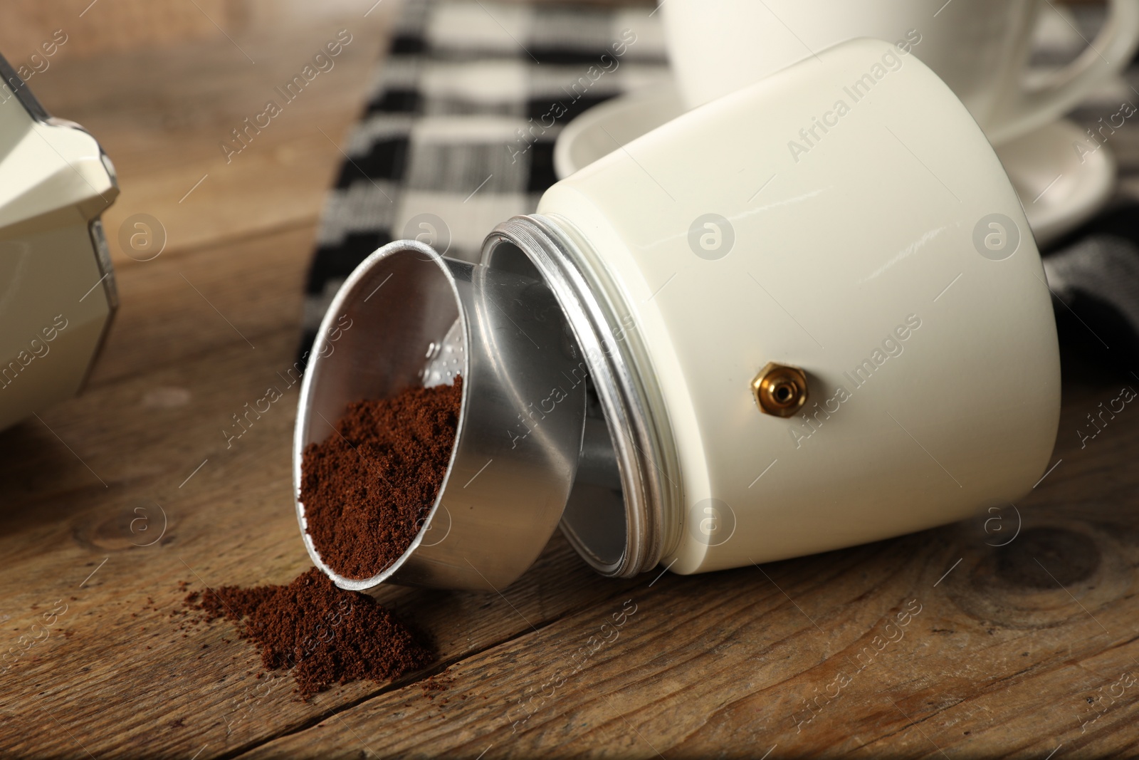 Photo of Moka pot and ground coffee on wooden table, closeup