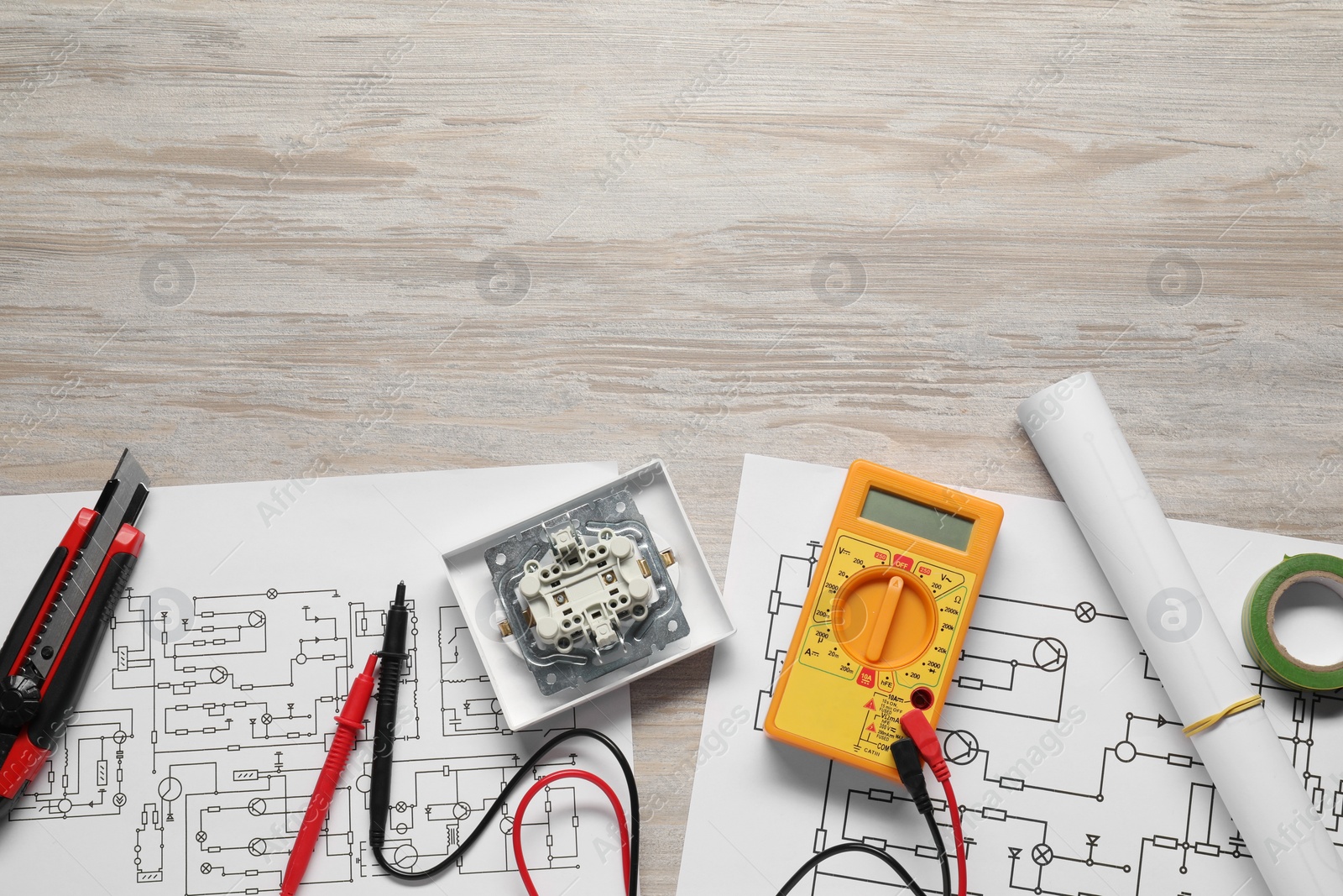 Photo of Wiring diagrams and digital multimeter on white wooden table, flat lay. Space for text