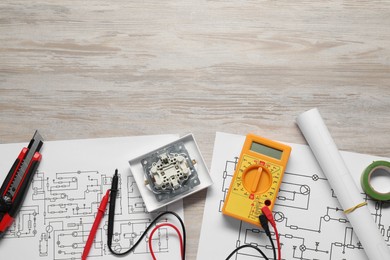 Photo of Wiring diagrams and digital multimeter on white wooden table, flat lay. Space for text